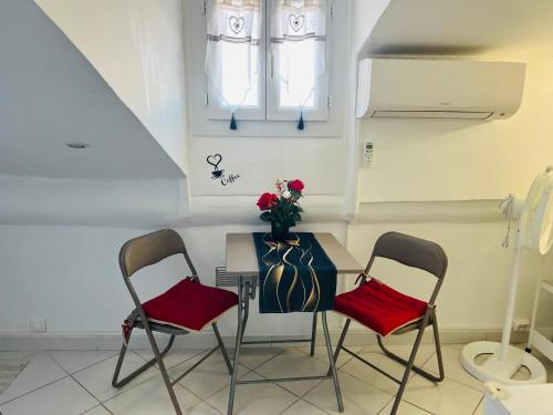 une table avec deux chaises et un vase de fleurs dans l'établissement Évasion Romantique sous les Toits Au Coeur du Vieux Nice, à Nice