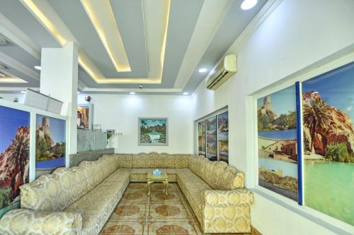 a living room with a large couch and paintings at OYO 140 Al Musafir Hotel in Barka