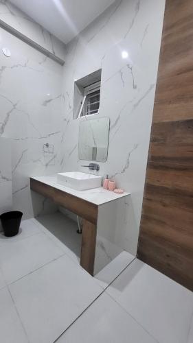 a white bathroom with a sink and a mirror at Buraans in Dehradun