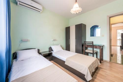two beds in a room with a desk and a chair at Sea&Park Apartment by Linas BNB in Varna City