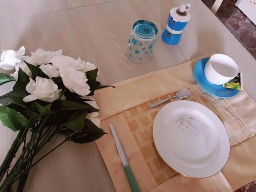 une table avec une assiette blanche et un vase de fleurs dans l'établissement Casa Nives in Villa Emilia, à Vietri