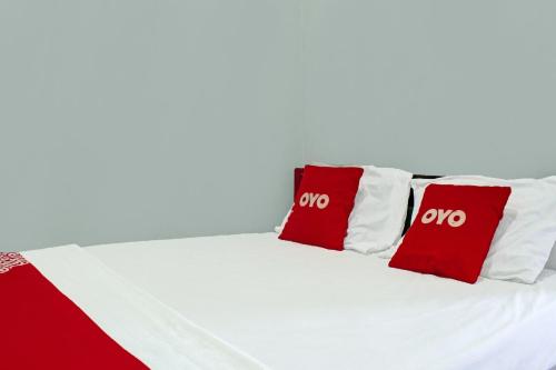 a bed with red and white pillows on it at Hotel O Yotowawa NearBukit Cinta in Kupang