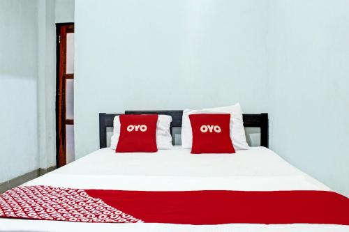 a bed with two red pillows on it at Hotel O Yotowawa NearBukit Cinta in Kupang