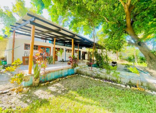 a small house with a porch and a tree at Bush Beach Backpackers in Vilanculos