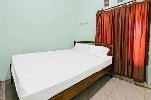 a bed in a room with a red curtain at Hotel O Homestay Bang HajiNearLapangan Penujak ( Inen Gonggang) in Praya