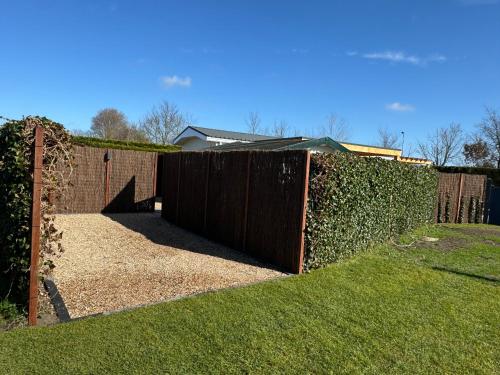 a fence with a wooden gate in a yard at ThuizInOuddorp Parel no 30 & Oester no 29 Verkoeling aan Zee in Ouddorp