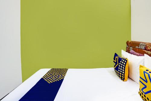 a bed with blue and yellow pillows on it at SPOT ON 91716 Kost Yy Syariah in Mojokerto