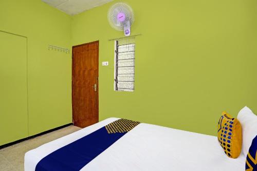 a green room with a bed and a fan at SPOT ON 91716 Kost Yy Syariah in Mojokerto