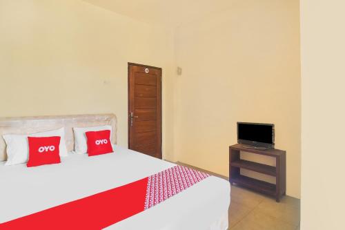 a bedroom with two beds with red pillows and a television at Hotel O Priska Kost Dan Homestay in Manado