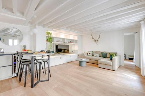 Il dispose d'une cuisine blanche et d'un salon avec une table et des chaises. dans l'établissement BnBNova - 2BR - La Seine & Saint Germain, à Paris
