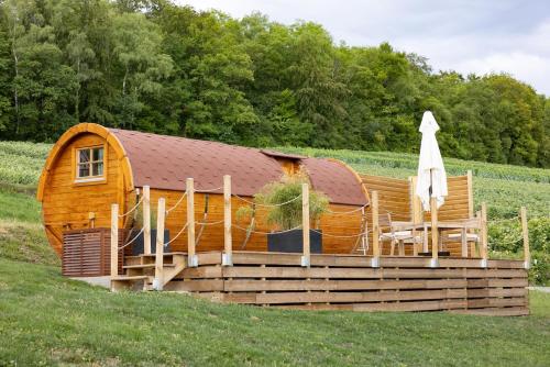 une cabane en bois dans un champ avec un parasol et des chaises dans l'établissement Expérience insolite : tonneau merveilleux, à Cormoyeux