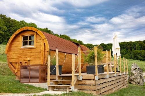 une cabane en bois avec une véranda et un parasol dans l'établissement Expérience insolite : tonneau merveilleux, à Cormoyeux
