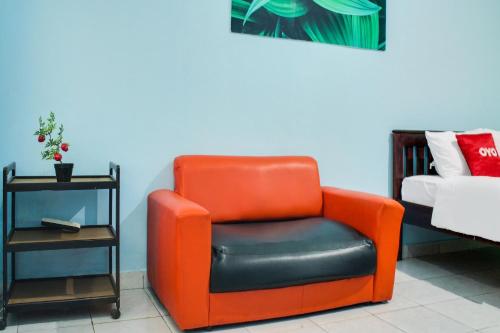 an orange chair sitting next to a bed at Hotel O Wisma Harapan Baik in Kupang