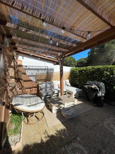 une terrasse avec une pergola en bois, une chaise et une table dans l'établissement Maison de vacance bord de mer, au Barcarès