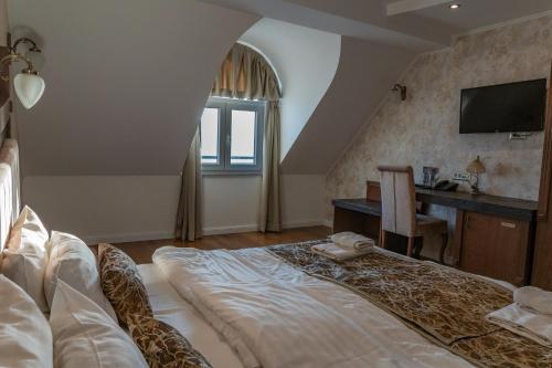 a bedroom with a bed and a desk and a television at City Palace Hotel in Ohrid