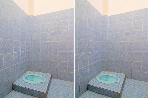 a bathroom with a blue toilet in a tiled wall at Hotel O Yoezef Homestay Syariah in Pekanbaru