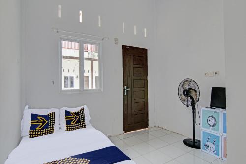 a bedroom with a bed and a window and a door at Hotel O Homestay Dinda Syariah Near Masjid Al Amin in Parit