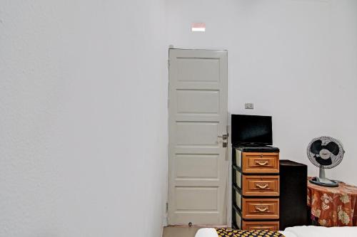 a room with a door and a desk and a television at Hotel O Homestay Dinda Syariah Near Masjid Al Amin in Parit