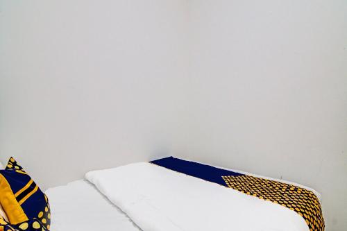a bedroom with two beds and a white wall at Hotel O Homestay Dinda Syariah Near Masjid Al Amin in Parit