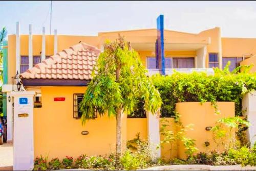 una casa amarilla con una palmera delante de ella en Lovista Hotel, en Haatso