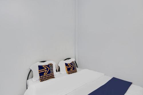 a white bed with three pillows on it at Hotel O Sg 99 Homestay Syariah Near SMP N 34 Pekanbaru in Parit