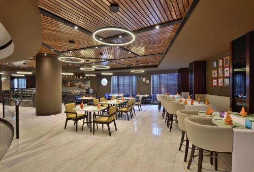 a dining room with tables and chairs in a restaurant at Radisson Gurugram Udyog Vihar in Gurgaon