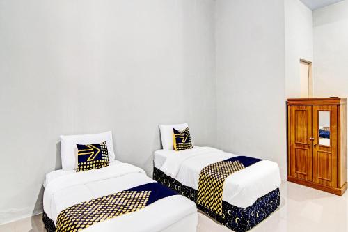 zwei Einzelbetten in einem Zimmer mit Schrank in der Unterkunft Hotel O Rumah Singgah Kinaya Syariah in Parit