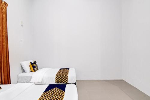 zwei Betten in einem Zimmer mit weißen Wänden in der Unterkunft Hotel O Rumah Singgah Kinaya Syariah in Parit