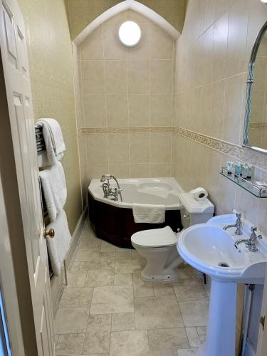 a bathroom with a tub and a toilet and a sink at Grafton Manor Hotel in Bromsgrove