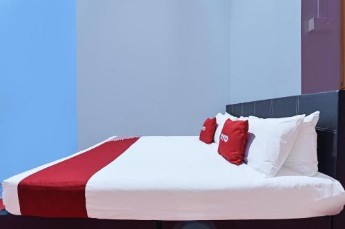 a bedroom with a bed with red and white pillows at Capital O 90664 Rabi Hotel in Kota Bharu