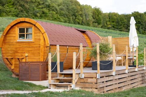 une grande cabine en bois avec une terrasse dans un champ dans l'établissement Nuit insolite : tonneau enchanté, à Cormoyeux