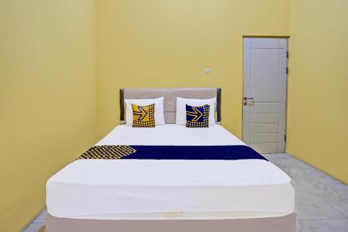 a bedroom with a large white bed with pillows at Hotel O Raffa Residence Syariah in Medokanayu