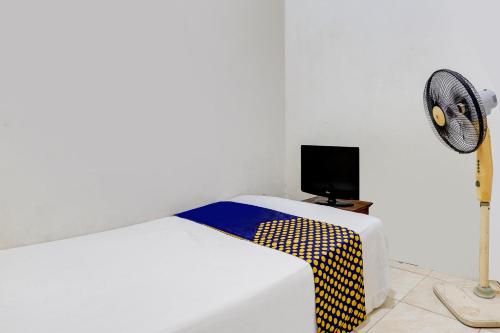 a white bedroom with a bed and a fan at OYO Life 91893 Kost Jeje Syariah in Tambak-kidul