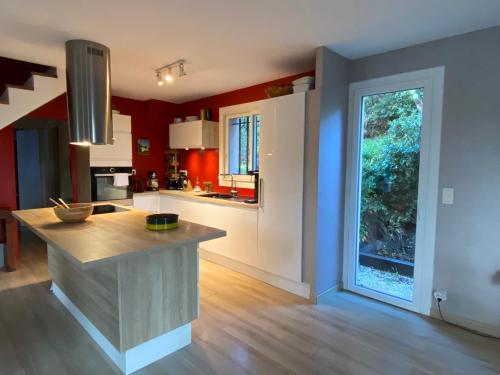 Il comprend une cuisine aux murs rouges et une grande fenêtre. dans l'établissement Les Arbousiers - villa climatisée avec piscine, au calme, à La Londe-les-Maures