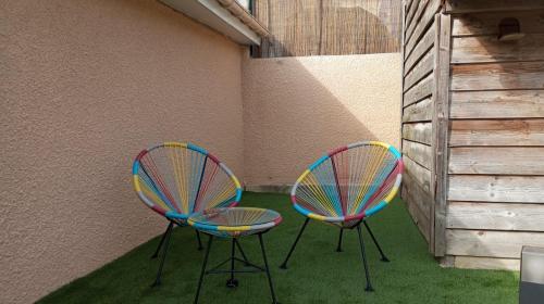 two colorful chairs sitting next to a wall at La Villa des Roses au cœur de Cormoyeux in Cormoyeux