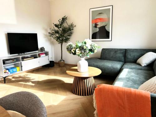 a living room with a couch and a table with flowers at Spacious boutique family apt w sunny balcony & mountain views in Zell am See