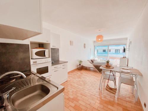 une cuisine avec un évier et une table à l'intérieur dans l'établissement Studio à 100m de la plage avec balcon - 66, à Canet