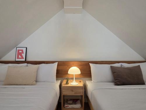 a room with two beds and a lamp on a table at Adellia Pension in Gyeongju