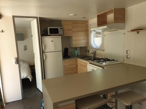 Il comprend une petite cuisine équipée d'un comptoir et d'un réfrigérateur. dans l'établissement Mobil Home Grand Confort, à Granges-Aumontzey