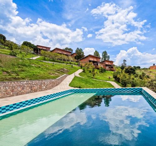 a swimming pool with blue water in front of houses at Umutuzo Lodge Kivu Lake in Buhoro