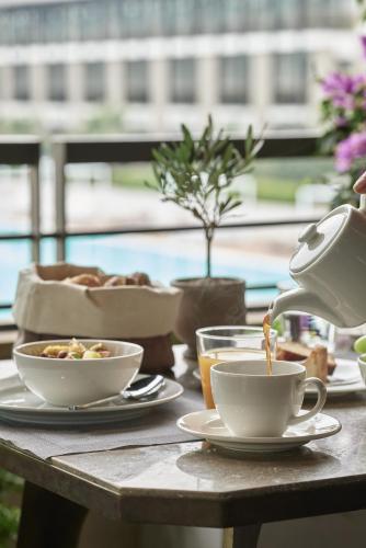 a teapot is pouring coffee into cups on a table at September Hotel Thessaloniki in Thessaloniki