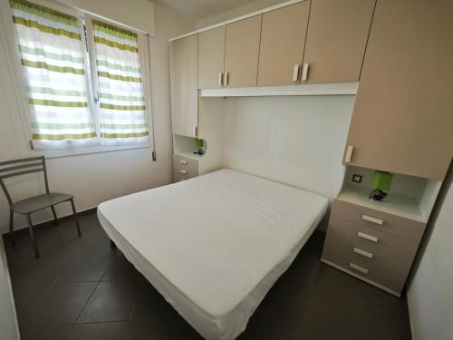 a small bedroom with a white bed and a chair at Patrizia in Rosolina