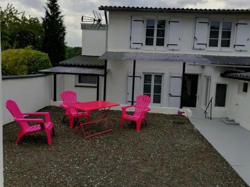 4 chaises roses et une table devant une maison dans l'établissement Maison villers sur mer 4 ou 6 PERSONNES, 2 CHAMBRES, PARKING GRATUIT, entre Deauville et Houlgate, RESERVATION UNIQUEMENT du samedi au samedi 7 nuits minimum CHEQUE de CAUTION DEMANDÉ, menage NON INCLUS, PETIT CHIEN ACCEPTÉ SAUF DANS LES CHAMBRES, à Villers-sur-Mer