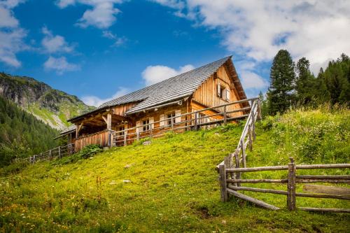a wooden cabin on a hill with a fence at Dorfergut in Weisspriach