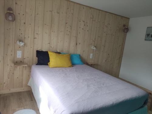 - un lit avec des oreillers jaunes et bleus dans l'établissement La Perlilounette, à Le Porge