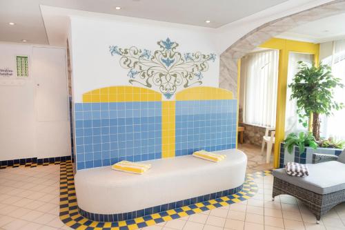 a lobby with a blue and yellow tile wall at Hotel Schneeberger in Niederau