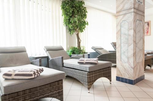 a patio with wicker chairs and a table at Hotel Schneeberger in Niederau