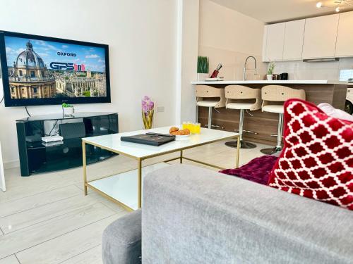 a living room with a couch and a table and a tv at Panorama House, Delightful 2-Bedroom Flat 1, Oxford in Oxford