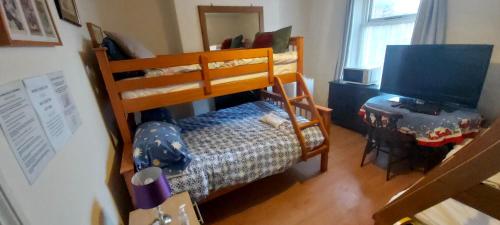 a bedroom with a bunk bed with a desk and a television at Phoenix Nights Guest House in Barrow in Furness