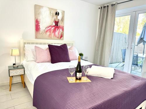 a bedroom with a bed with a bottle of wine on a table at Panorama House, Delightful 2-Bedroom Flat 1, Oxford in Oxford